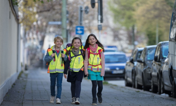 3 Kinder mit reflektierender Warnweste auf dem Schulweg