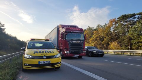 Ein ADAC Pannenfahrzeug auf dem Standstreifen einer Autobahn. Rechts daneben ein LKW und ein PKW.