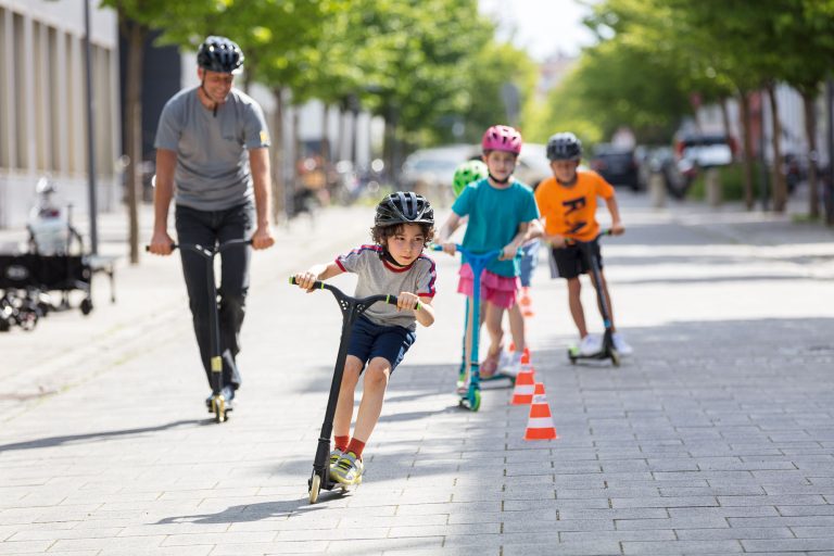Kinder in einer Fußgängerzone beim Roller-Training