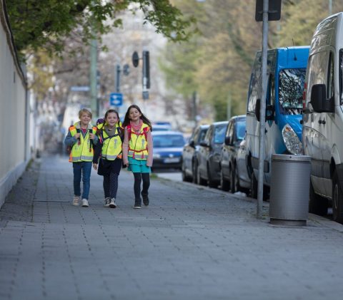 Drei Kinder auf dem Weg zur Schule, mit Sicherheitswarnwesten