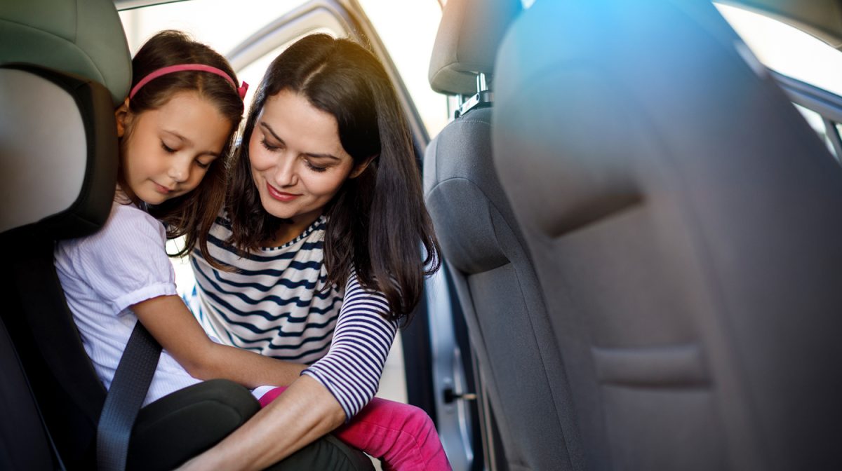 Eine Mutter schnallt ihr Kind im Auto an.