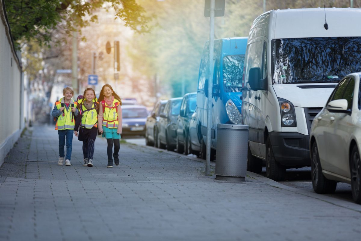 Drei Kinder in Sicherheitswarnwesten auf dem Weg zur Schule