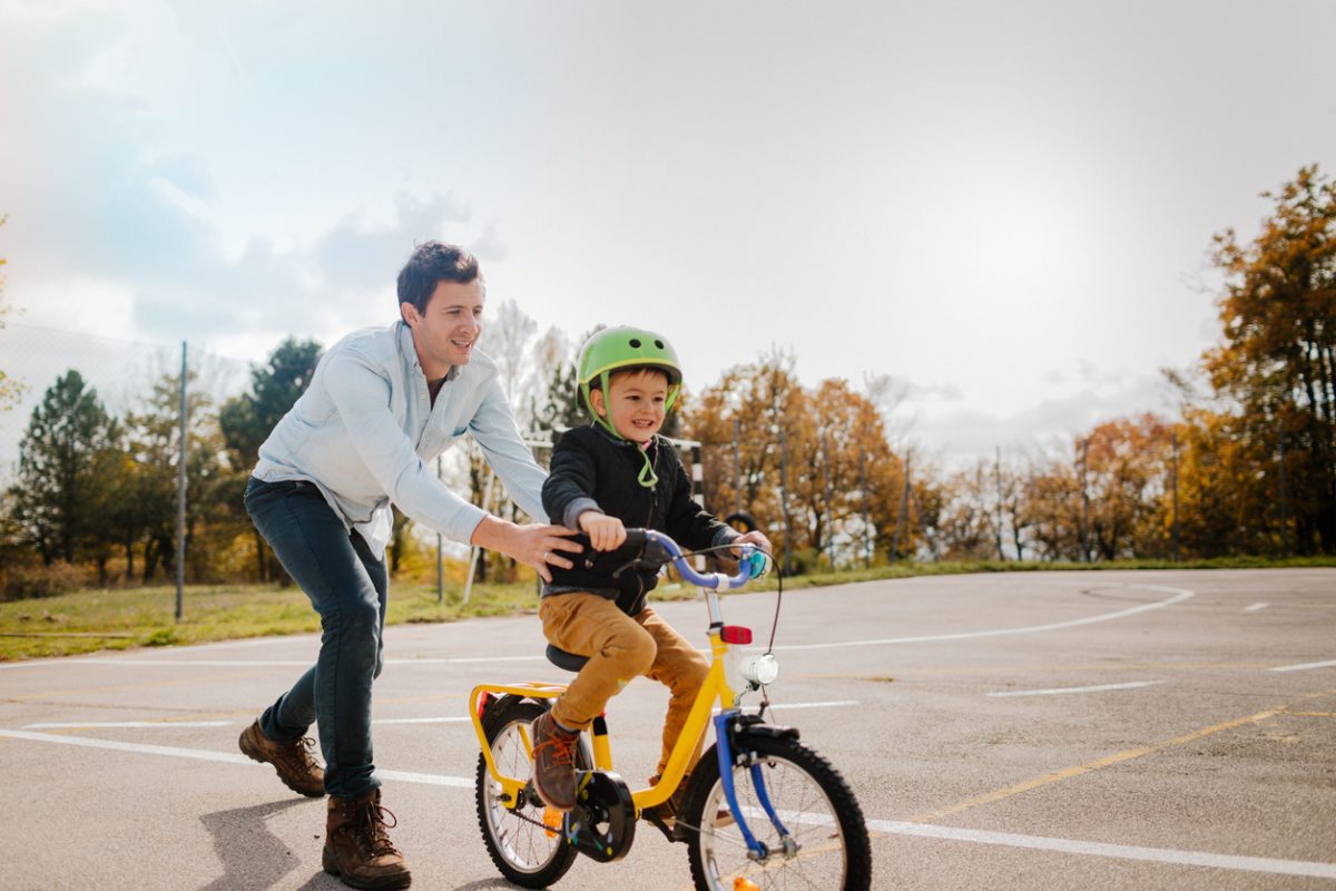 Ein Vater mit seinem Sohn auf einem Übungsplatz. Sie üben Fahrrad fahren.