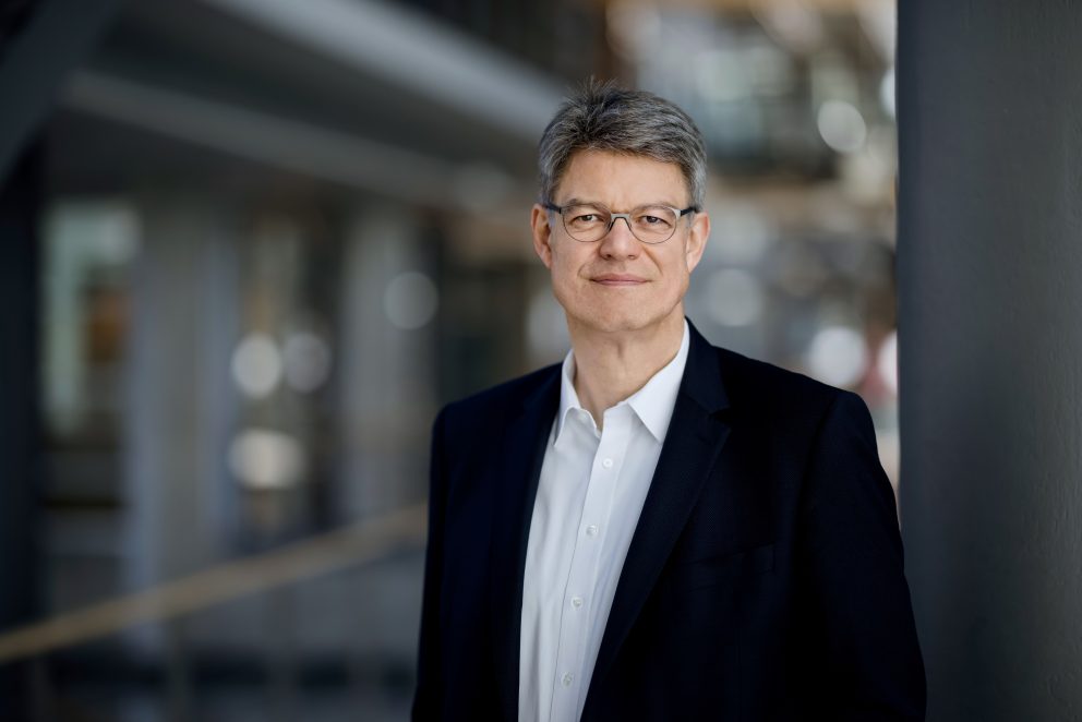 Porträtfoto von Verkehrsminister Schnieders, der in die Kamera blickt und leicht lächelt. Er trägt ein weißes Hemd und ein schwarzes Sakko.